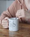 Un mug en céramique essendu entre les mains d'une femme qui boit son café, une tasse pour café ou thé fabriqué en france, azamoul mode et accessoires berbères amazigh et décoration intérieure