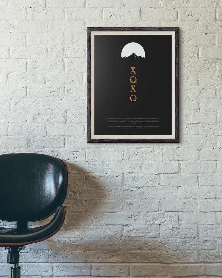 Un cadre d'une affiche murale de Djurdjura écrit en alphabet Tifinagh accroché à un mur à coté d'une chaise par Azamoul mode et accessoires berbères amazigh et décoration intérieure
