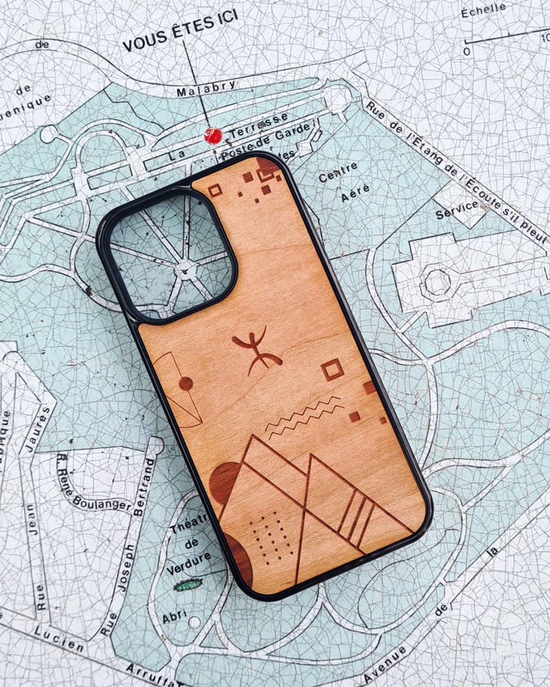 Coque en bois Abstract Amazigh l'univers amazigh berbère par Azamoul mode et accessoires berbères pour iPhone posée sur une carte de quartier