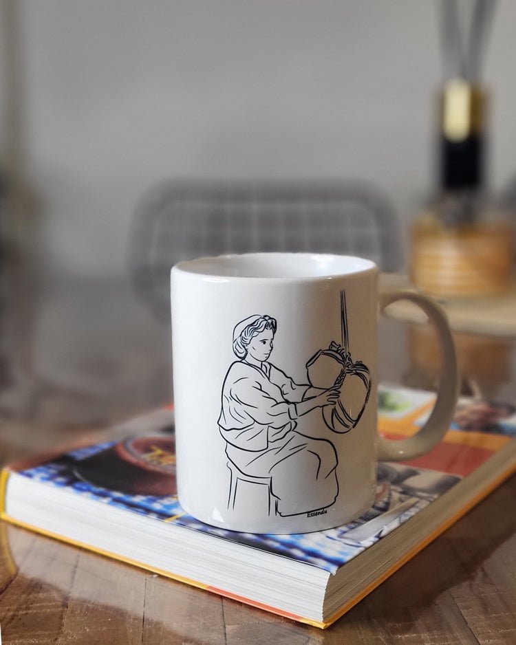 Un mug en céramique essendu blanc posé sur un livre par azamoul mode et accessoires berbères amazigh, fabriqué en France