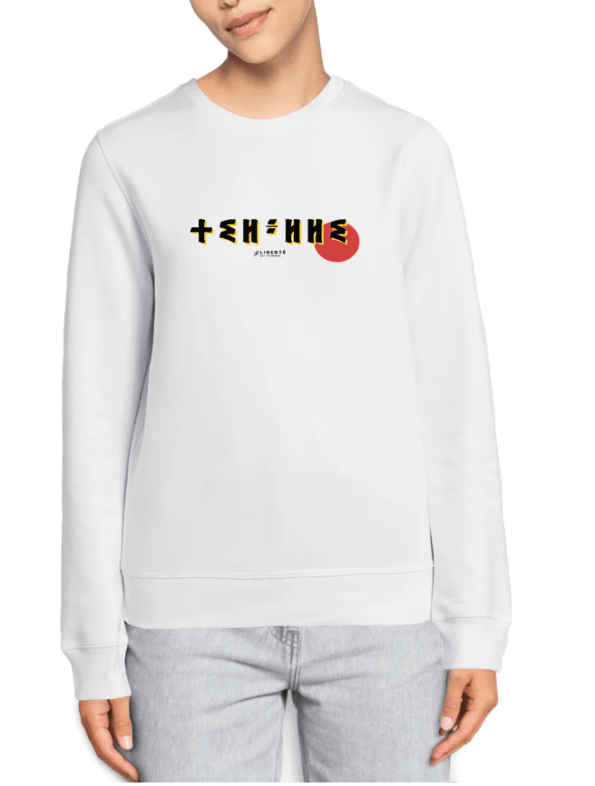 femme qui porte un pull thilelli liberte 100% coton bio, écrit en langue tifinagh, la langue des berbères amazigh par Azamoul mode et accessoires berbères, de couleur blanc
