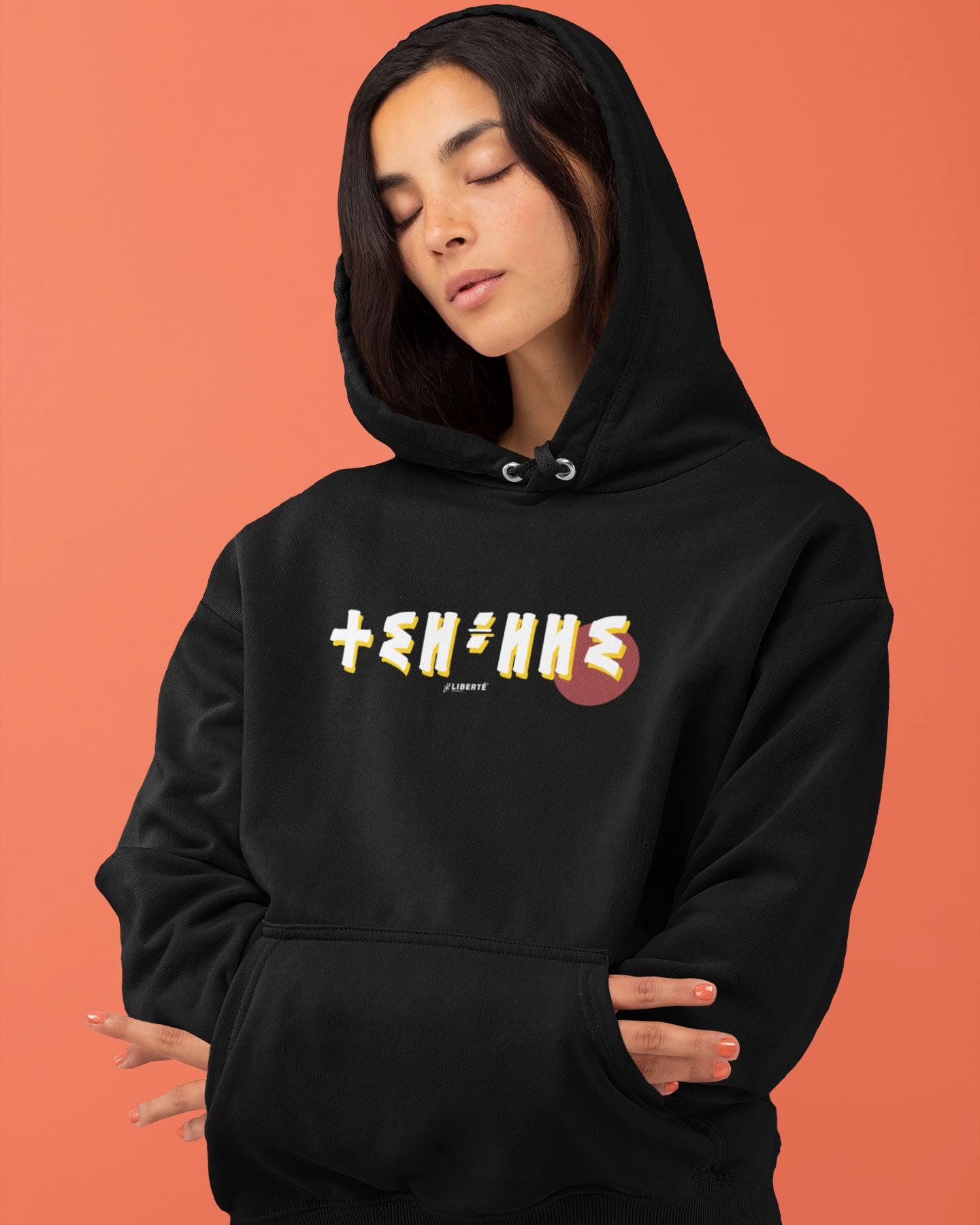 Femme qui porte un sweat à capuche thilelli liberte 100% coton bio, écrit en langue tifinagh, la langue des berbères amazigh par Azamoul mode et accessoires berbères, de couleur noir