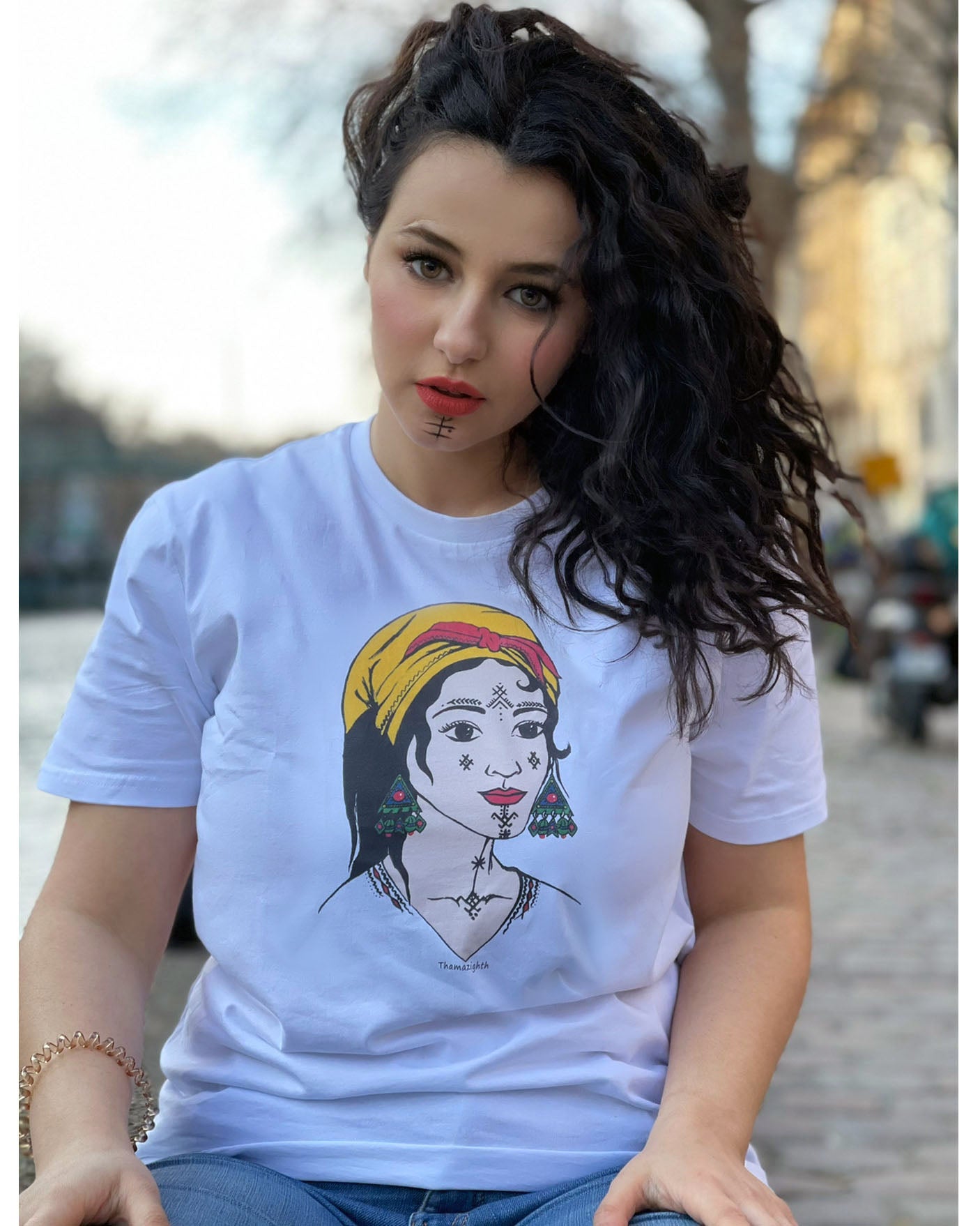 Alycia femme porte t-shirt femme berbère kabyle amazigh de azamoul blanc
T-shirt blanc femme berbère Amazigh par Azamoul Mode et Accessoires Berbères : design traditionnel avec tatouage facial symbolique, foulard kabyle amendil coloré, bijoux berbères et symbole berbère. Portez votre identité fièrement