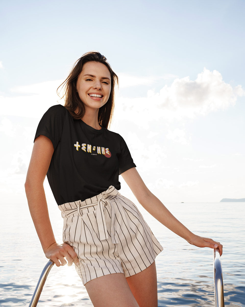 Femme sur un bateau en été porte le t-shirt Thilelli écrit liberté en tifinagh par azamoul mode et accessoires berbères amazigh de couleur noir