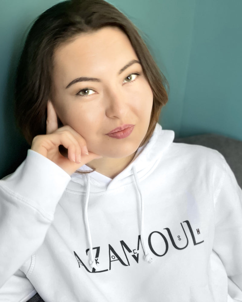 sweat a capuche portée par une femme aux cheveux longs, avec le logo azamoul écrit en tifinagh qui signifie symbole en langue berbère amazigh tifiangh, portez votre identite, par azamoul mode et accessoires berbères