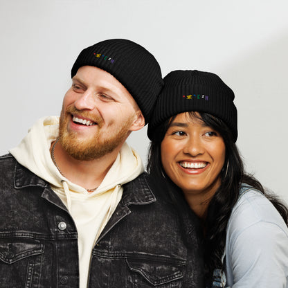 Homme et femme qui sourient portants le bonnet de pécheur brodé Azamul en Tifinagh, l'alphabet amazigh, par Azamoul mode et accessoires berbères. Le bonnet de couleur noire