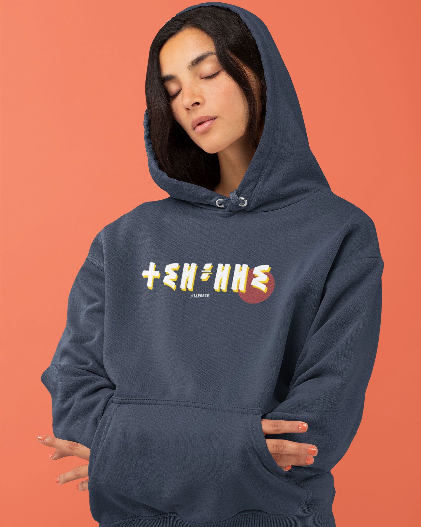 Femme qui porte un sweat à capuche thilelli liberte 100% coton bio, écrit en langue tifinagh, la langue des berbères amazigh par Azamoul mode et accessoires berbères,  de couleur marine