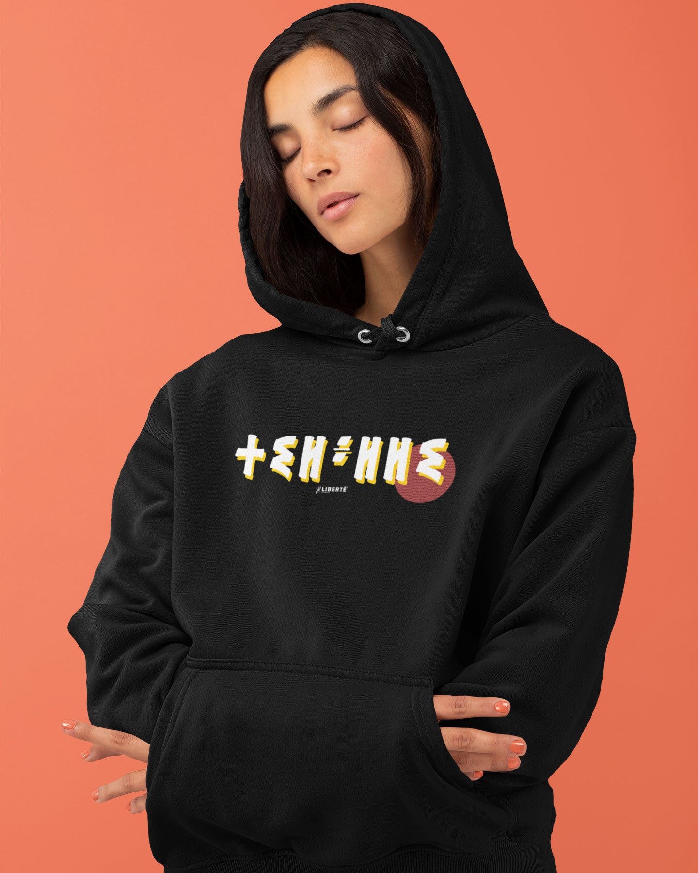 Femme qui porte un sweat à capuche thilelli liberte 100% coton bio, écrit en langue tifinagh, la langue des berbères amazigh par Azamoul mode et accessoires berbères,  de couleur noir