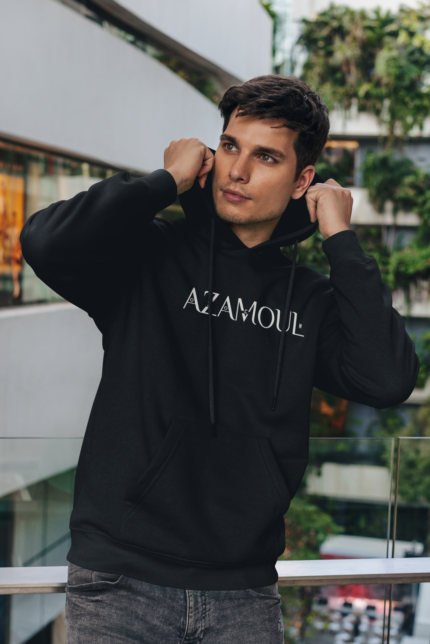 Sweat à capuche Azamoul écrit en tifinagh porté par un homme dans un immeuble regardant de loin, par azamoul mode et accessoires berbères amazigh couleur noir