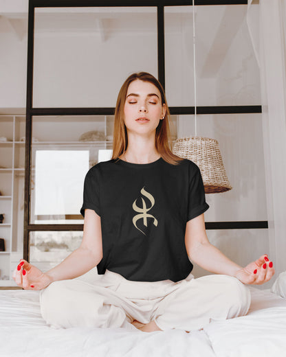 Femme dans sa chambre en position de méditation portant un tshirt amazigh yaz noir par azamoul mode et accessoires berbères