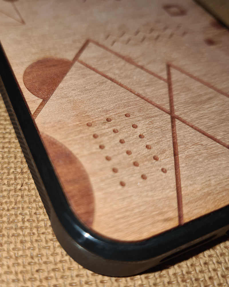 Une coque en bois Xiaomi abstract amazigh debout sur une table dans un parc avec un pin à coté par Azamoul mode et accessoires berbères