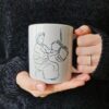mug-essendou-made-in-franceazamoul-628228_a8ea14ff-64f6-404e-883c-b6d97d489089 Un mug essendu une tradition kabyle amazigh berbère tenu par une femme avec ses mains, une tasse pour café ou thé fabriqué en france, azamoul mode et accessoires berbères amazigh et décoration intérieure