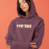 Femme qui porte un sweat à capuche thilelli liberte 100% coton bio, écrit en langue tifinagh, la langue des berbères amazigh par Azamoul mode et accessoires berbères,  de couleur bordeaux