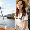 Femme sur un bateau en été porte le t-shirt Thilelli liberté par azamoul mode et accessoires berbères amazigh de couleur blanche