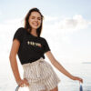Femme sur un bateau en été porte le t-shirt Thilelli écrit liberté en tifinagh par azamoul mode et accessoires berbères amazigh de couleur noir