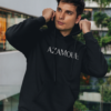 Sweat à capuche Azamoul écrit en tifinagh porté par un homme dans un immeuble regardant de loin, par azamoul mode et accessoires berbères amazigh couleur noir