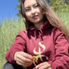 sweat à capuche YAZ avec le symbole berbère amazigh YAZ , symbole du peuple libre amazigh, par azamoul mode et accessoires berbères de couleur bordeaux, portée par une femme aux cheveux longs qui tient une fleur  dans un champ