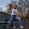 T-shirt Liberté Fatma Nsoumer porté par Taryel 2.0 dans un parc avec tatouages berbères et qui fait un geste de victoire - Azamoul mode et accessoires amazighs - Imprimé en France - 100% Coton Bio