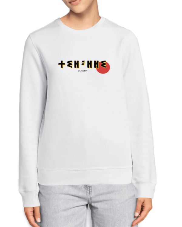 femme qui porte un pull thilelli liberte 100% coton bio, écrit en langue tifinagh, la langue des berbères amazigh par Azamoul mode et accessoires berbères,  de couleur blanc