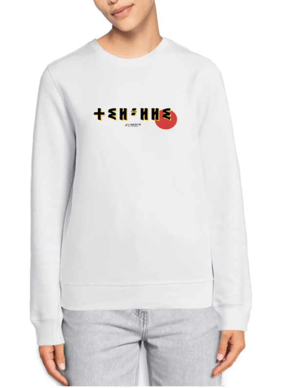 femme qui porte un pull thilelli liberte 100% coton bio, écrit en langue tifinagh, la langue des berbères amazigh par Azamoul mode et accessoires berbères,  de couleur blanc